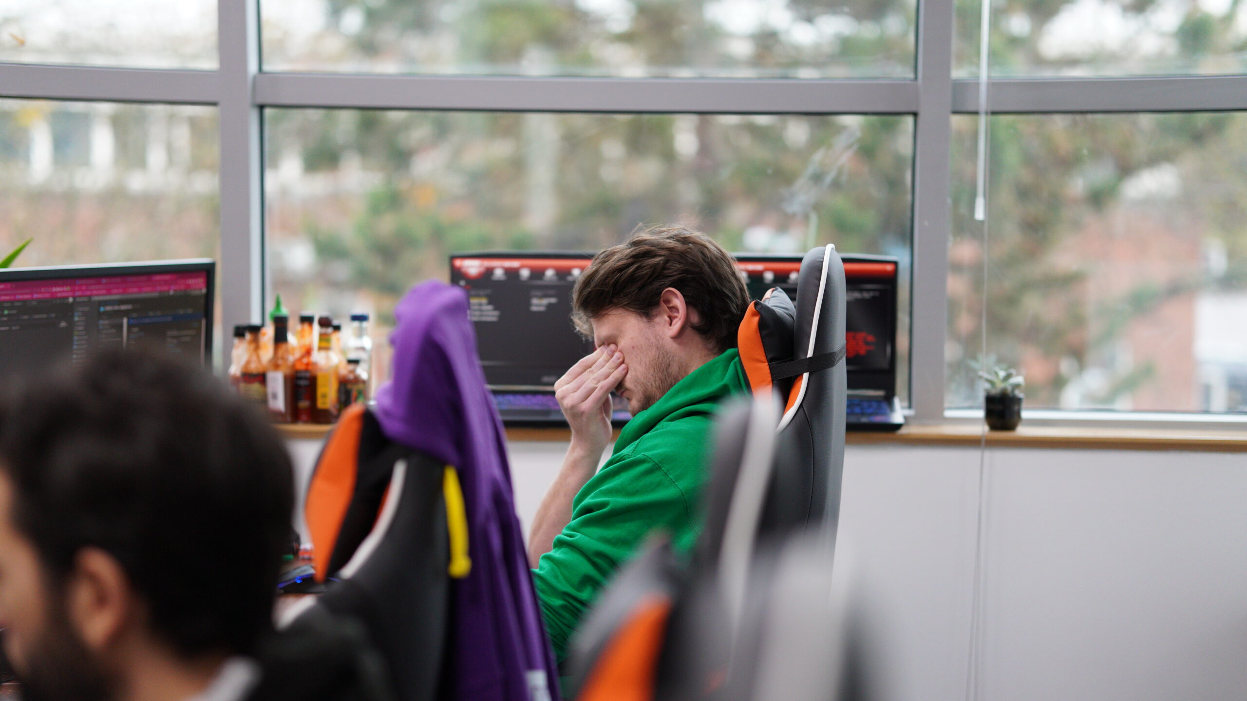 Photo of a software engineer rubbing his eyes in tired frustration